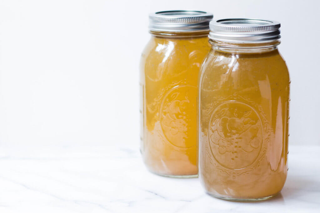 large mason jars of bone broth on a marble slab