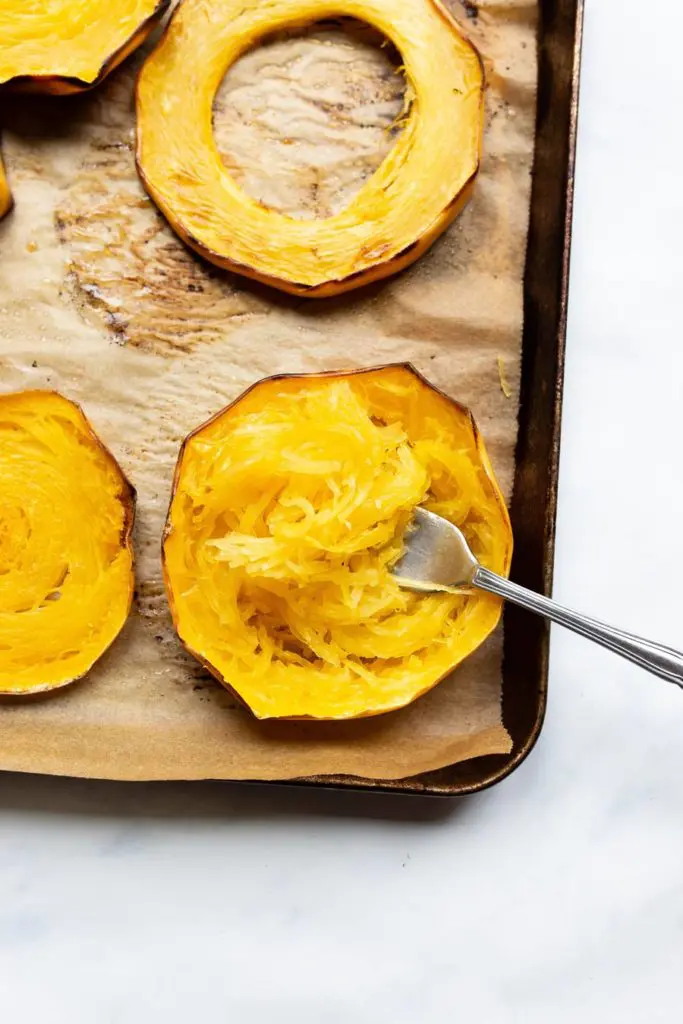 roasted spaghetti squash rings on a parchment lined baking sheet with fork