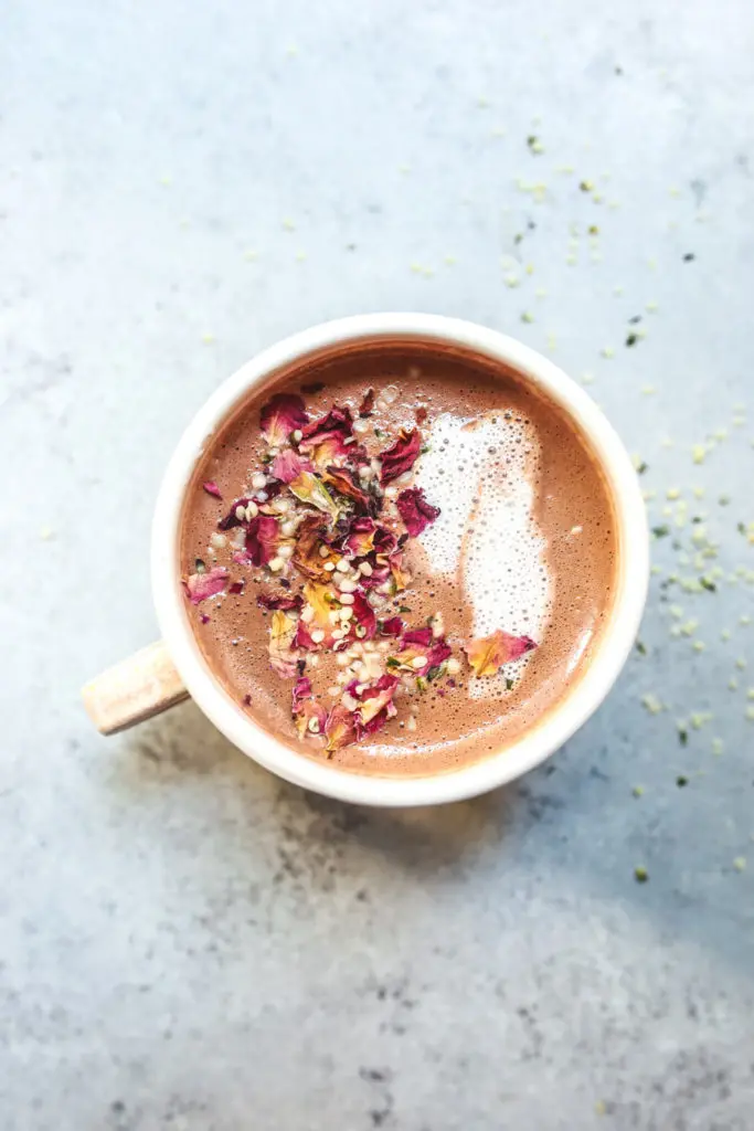 hot cocoa in a mug with rose petals and milk