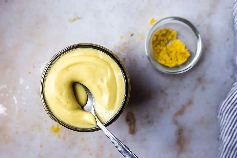 overhead photo of cashew cheese sauce in mason jar with spoon 