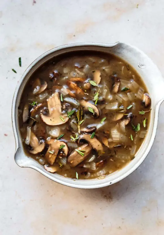 homemade herbed mushroom gravy in a bowl with fresh herbs