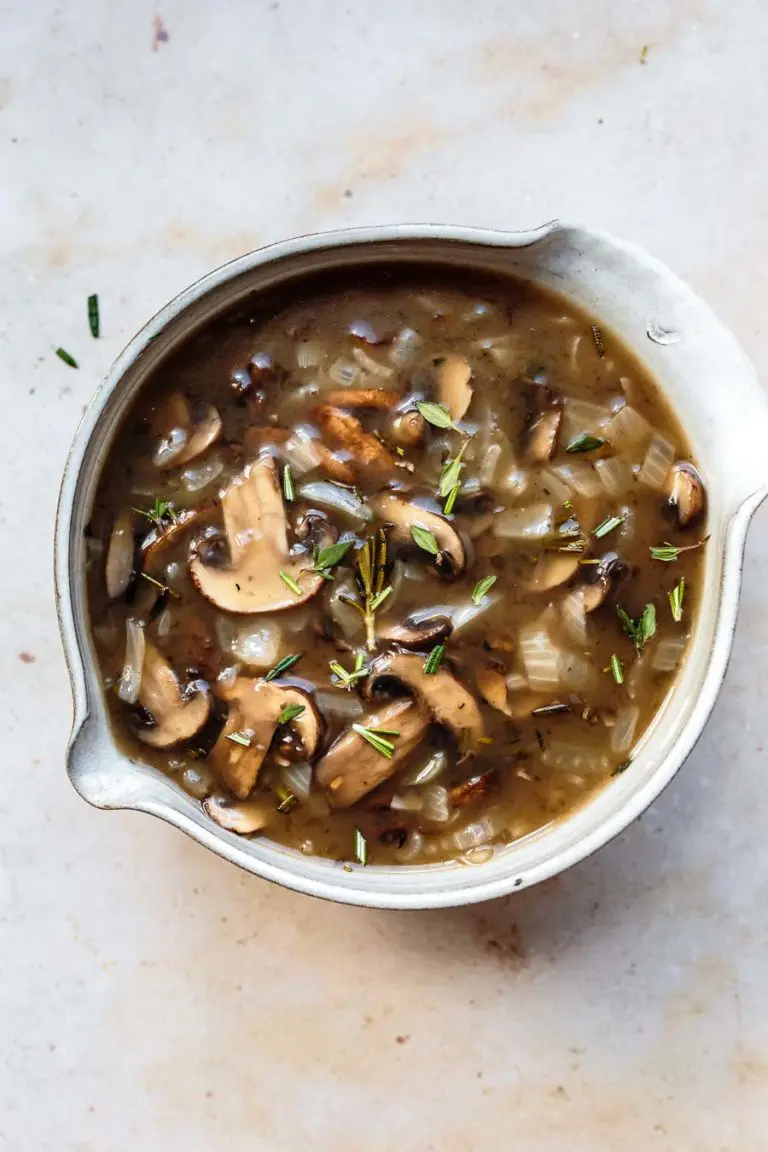 homemade herbed mushroom gravy in a bowl with fresh herbs