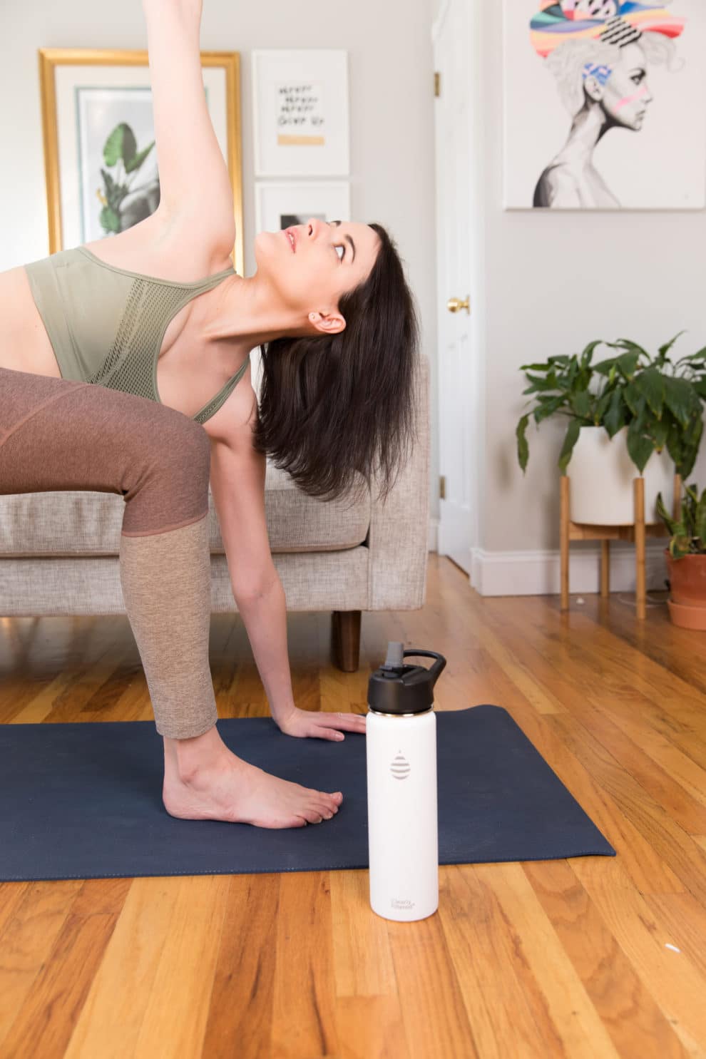 woman doing yoga on a mat with a Clearly Filtered water bottle beside her