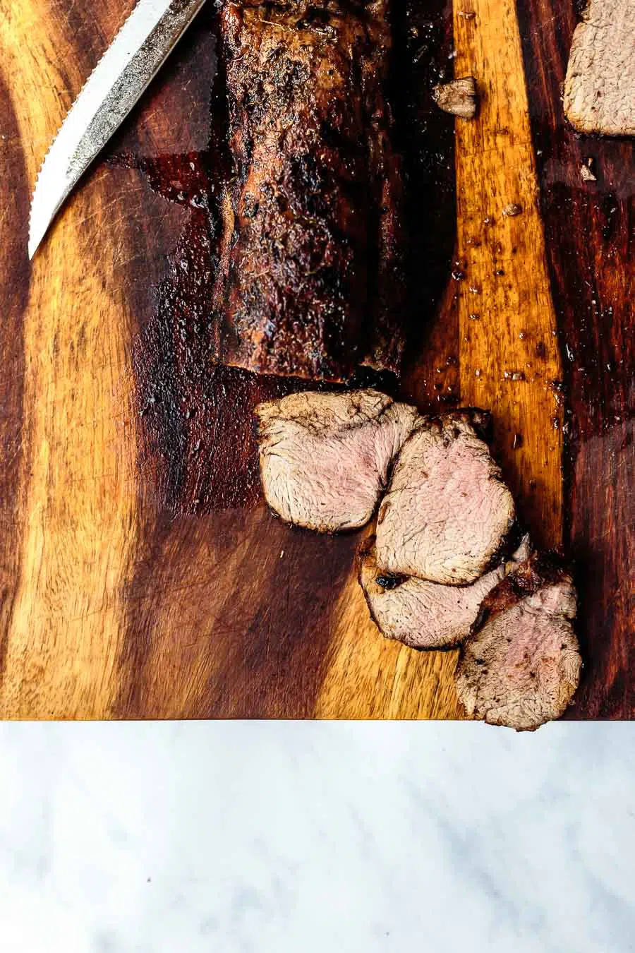 sliced balsamic pork tenderloin on cutting board