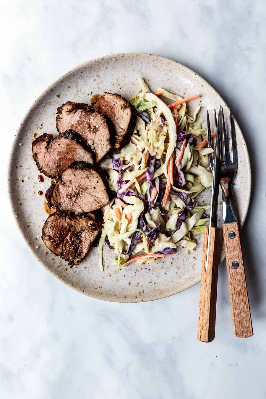 sliced balsamic pork tenderloin with coleslaw on a plate