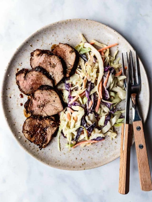 sliced balsamic pork tenderloin with coleslaw on a plate