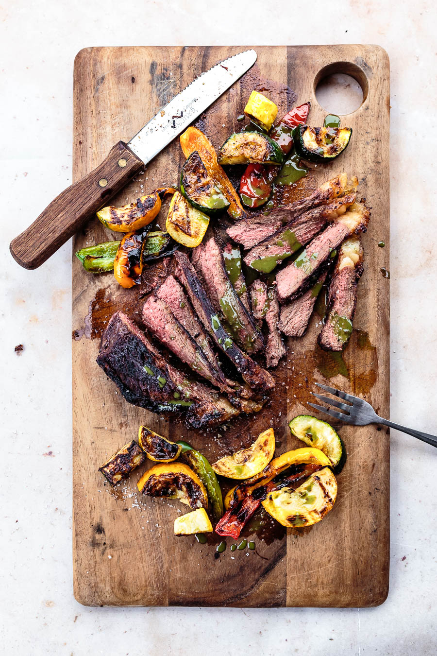 grilled picanha steak with vegetables and chimichurri served on a cutting board
