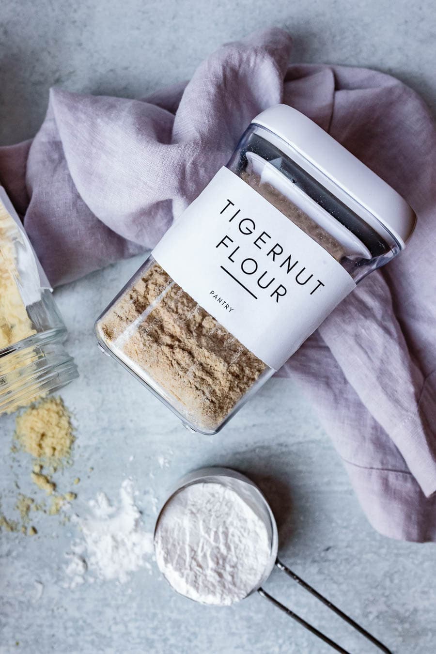 gluten-free flours in glass jars with measuring cups coconut flour tigernut flour and almond flour