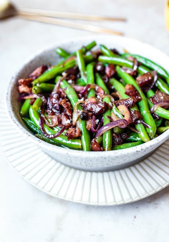 this warm green beans salad with bacon in a white serving bowl