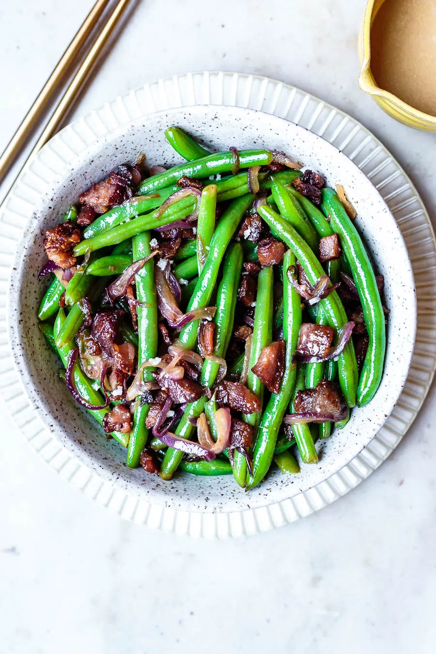 this warm green beans salad with bacon in a white serving bowl