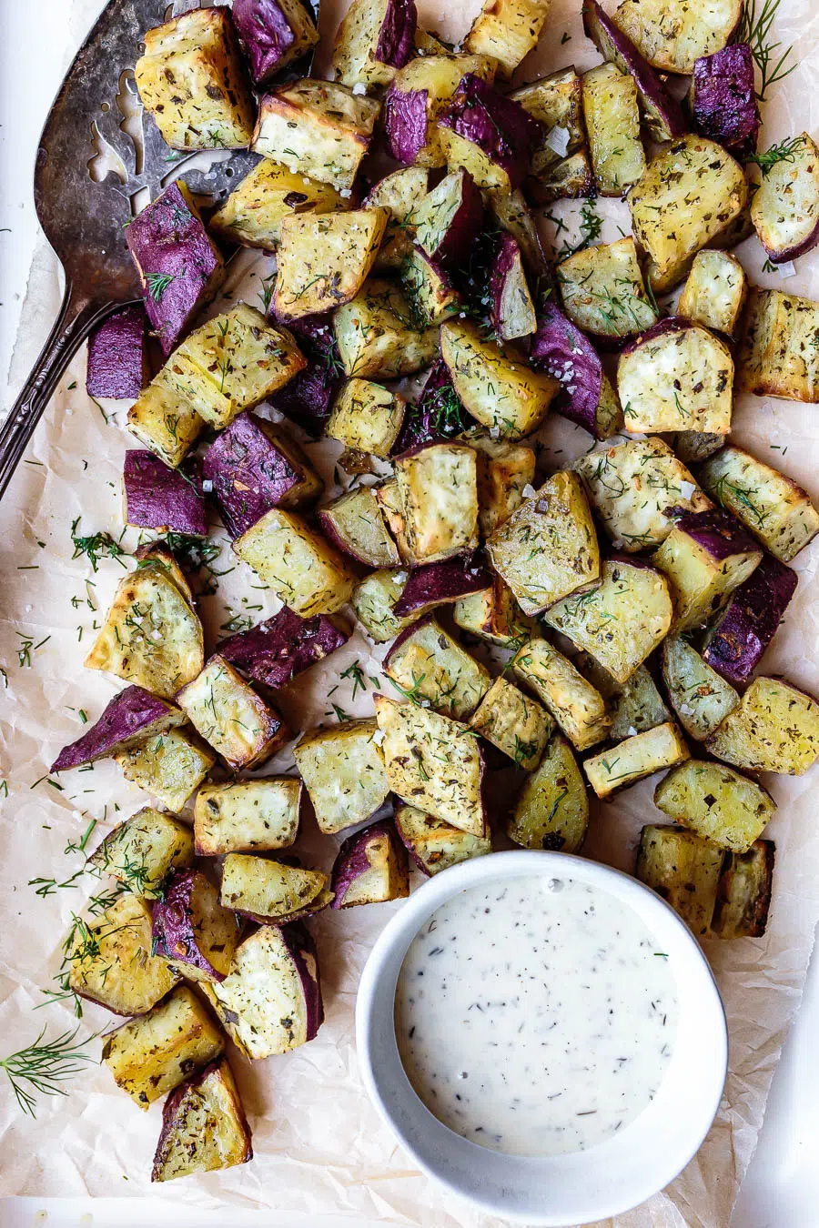 roasted ranch sweet potatoes on a baking sheet with dipping sauce