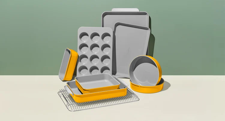 Caraway healthy nonstick cookware in the baking selection in yellow. There is a muffin or cupcake tray, 2 circular cake tins, a variety of rectangular cake pans, some sheet trays and a cooling rack.