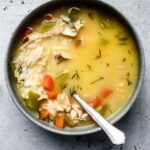 creamy chicken avgolemono soup in a bowl with fresh dill and lemon
